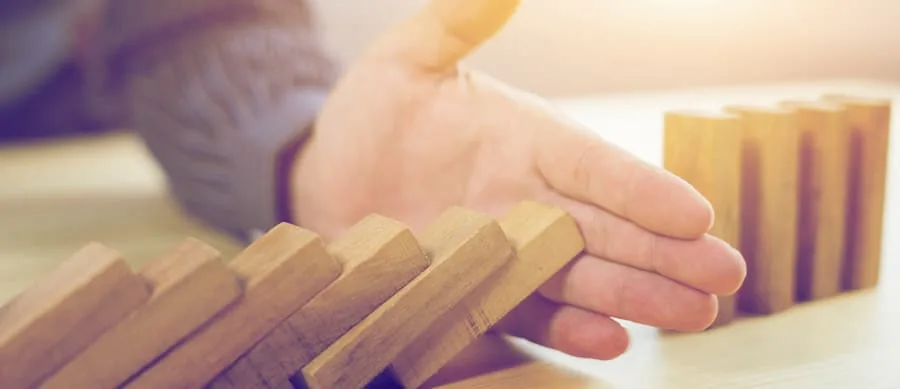 man stopping dominoes from falling