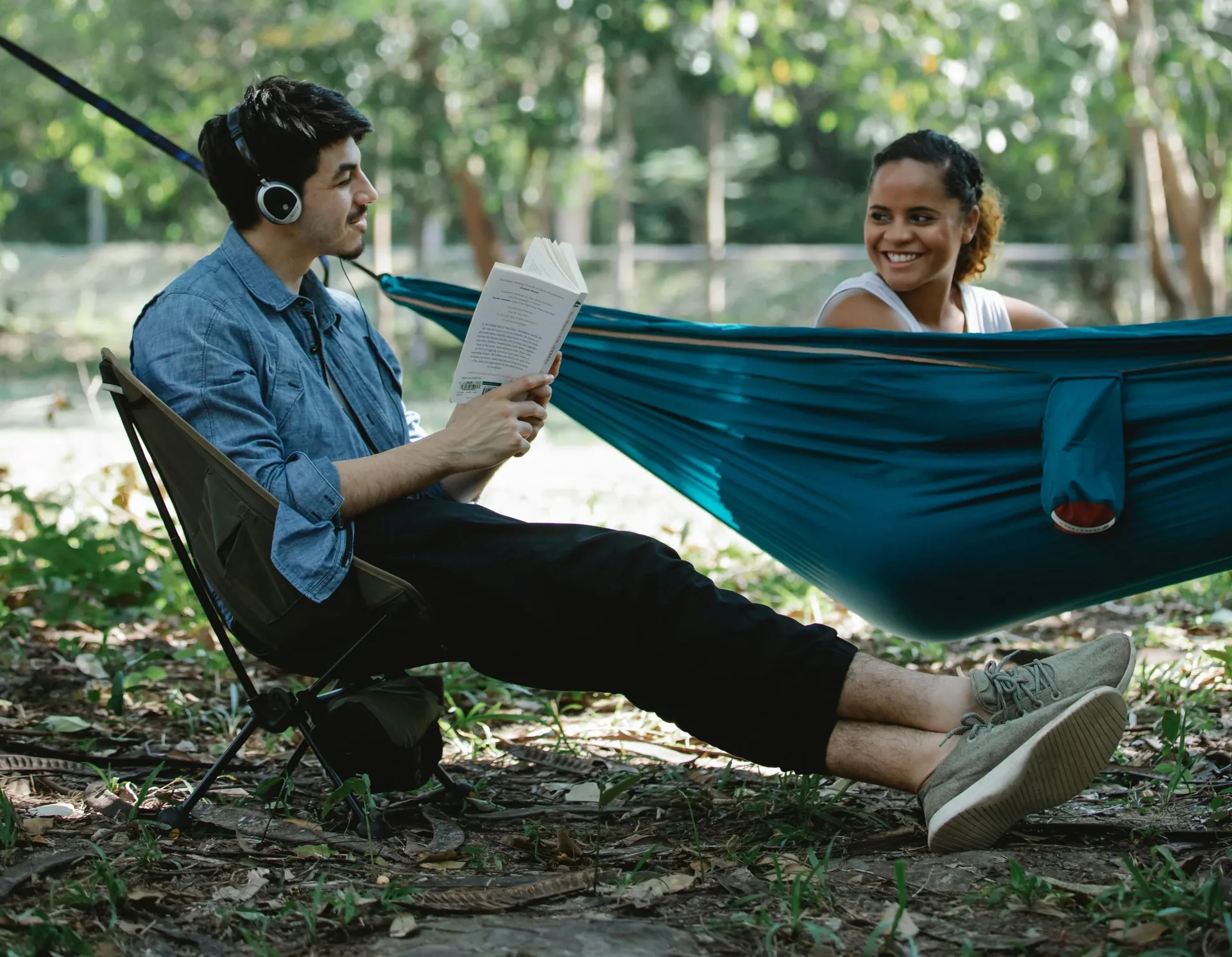Two sober friends having fun reading and relaxing in a hammock