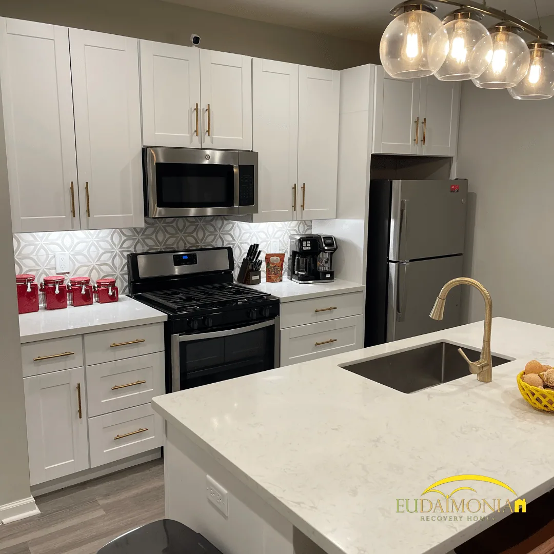 Kitchen with white cabinets, stainless range and microwave, and a quartz island with an undermount sink.