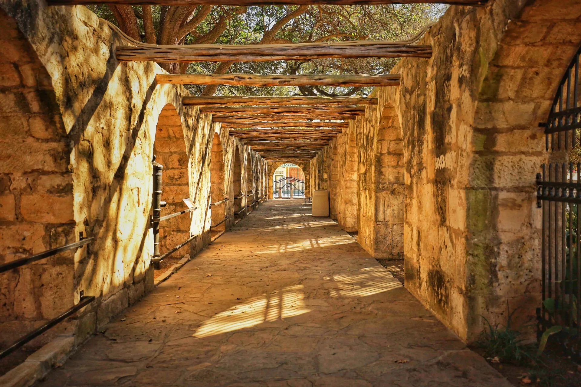 Sunlit stone corridor at a historic mission in San Antonio.