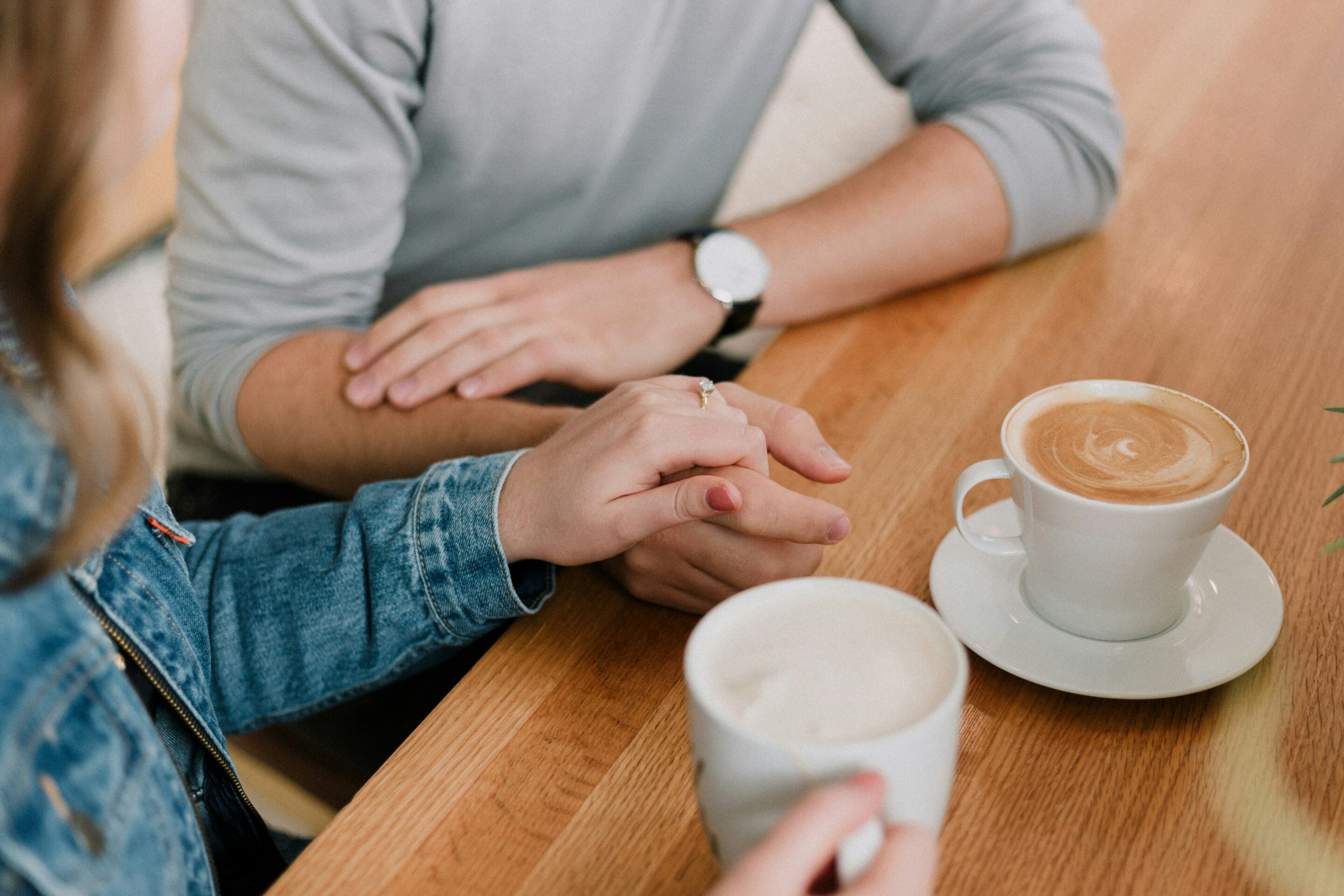 Close-up of two people holding hands during supportive outpatient recovery conversation.