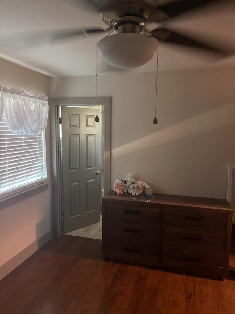 Private bedroom in Austin sober living home with dresser, ceiling fan, and natural window light
