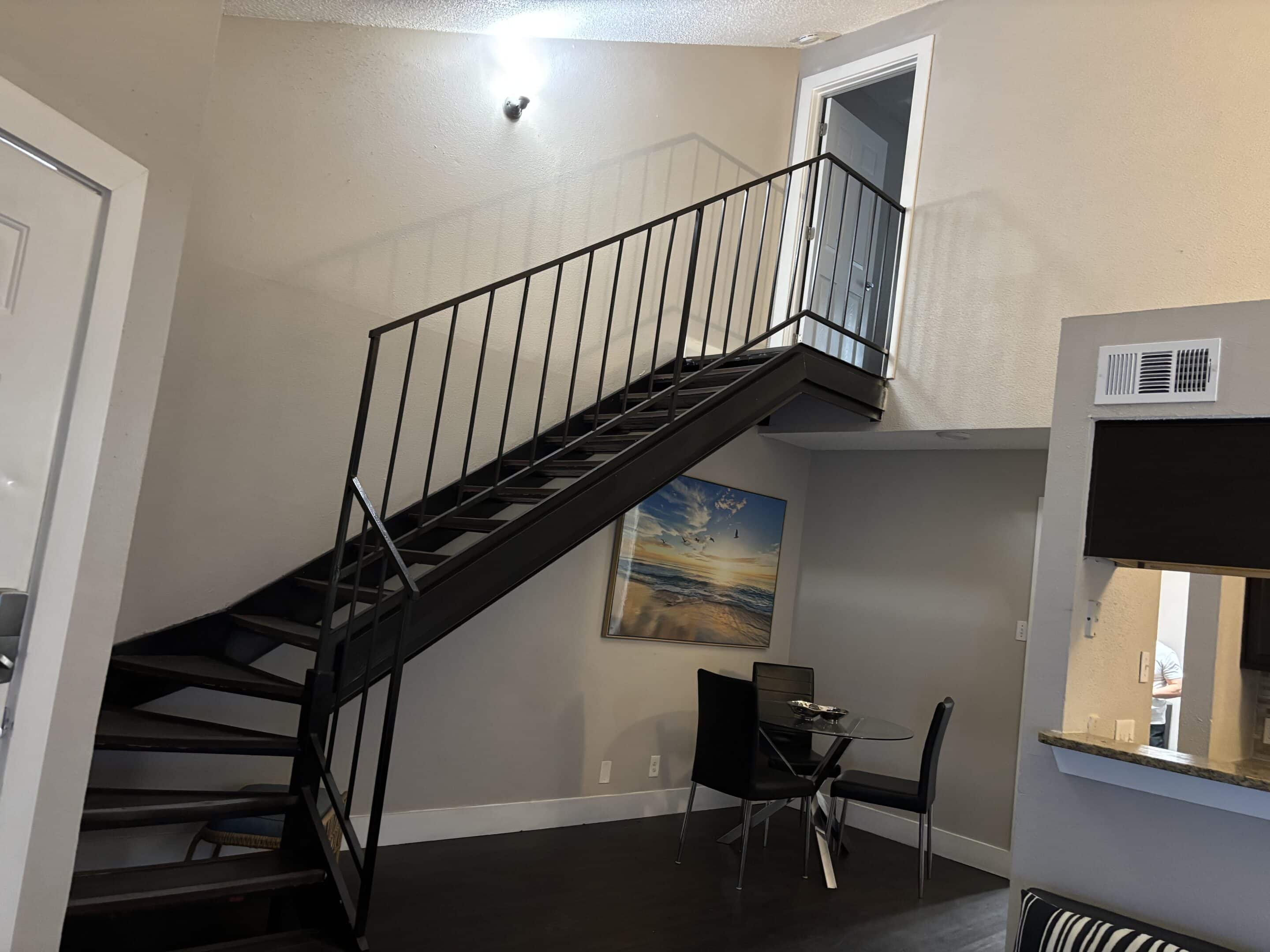 Two-bedroom men’s sober living apartment in Austin with loft-style staircase and dining area