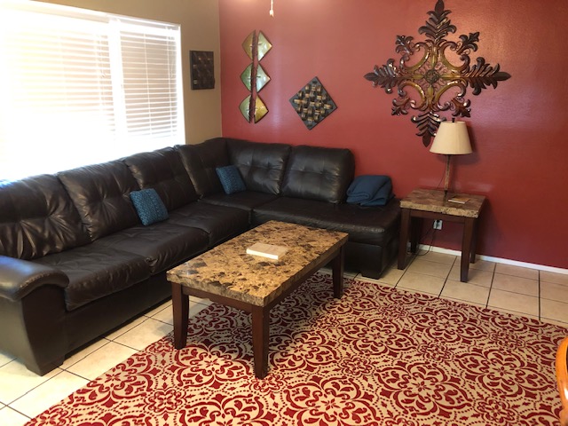 Living room with sectional sofa and decorative wall art at Parkfield Drive women’s sober living home in Austin.
