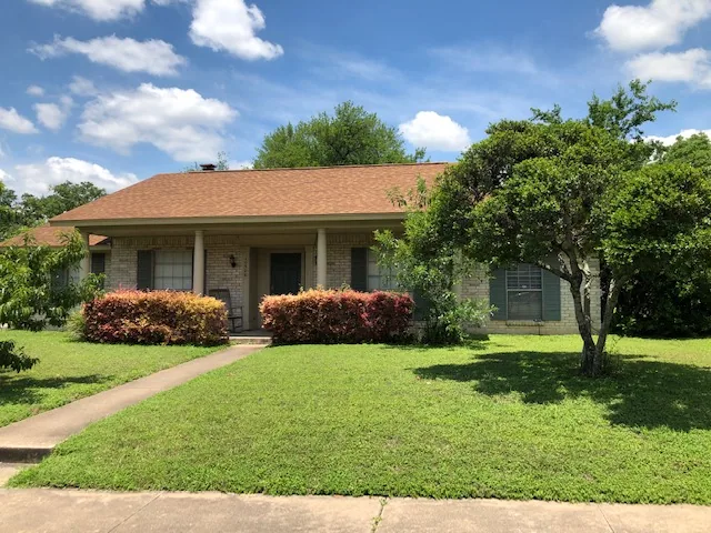 Front view of Eudaimonia’s Parkfield Drive women’s sober living home in Austin, Texas with green lawn and brick exterior.
