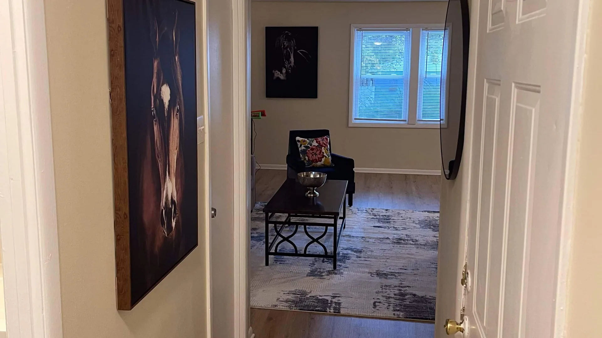 View through a doorway into the living room, with framed artwork and a coffee table beyond.