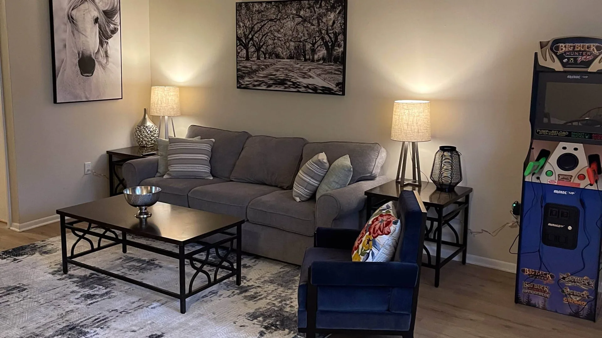 Living room with a gray sectional, two table lamps, a blue armchair and a metal-framed coffee table.