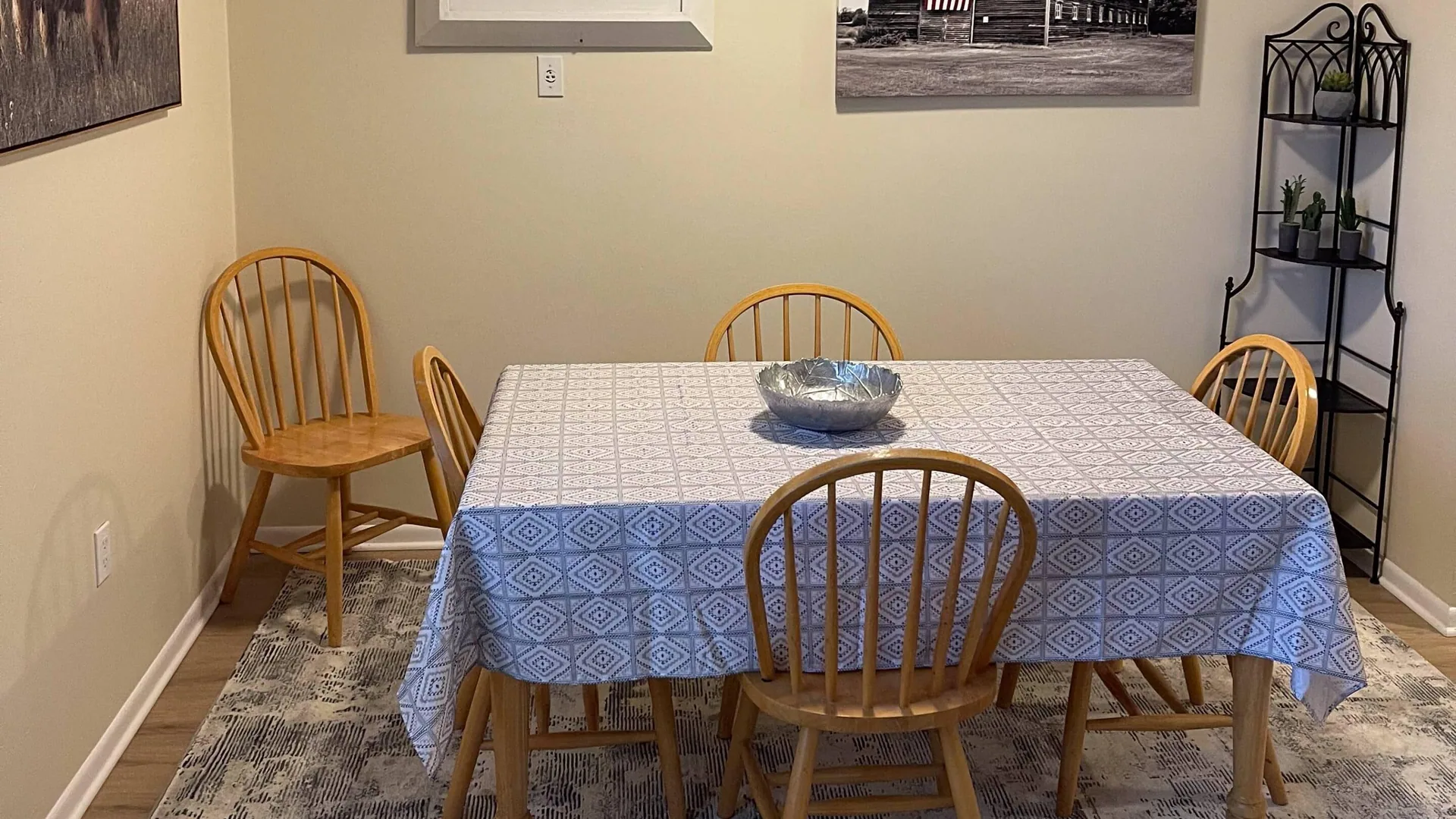 Dining table under a blue checked cloth with wooden spindle chairs.