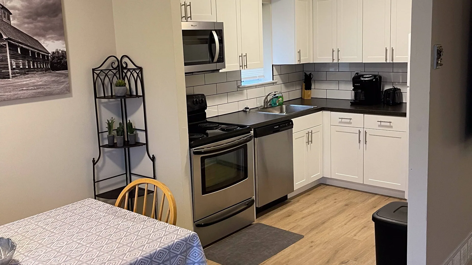 Kitchen with white cabinets, a stainless range and microwave, and a gray tile backsplash.