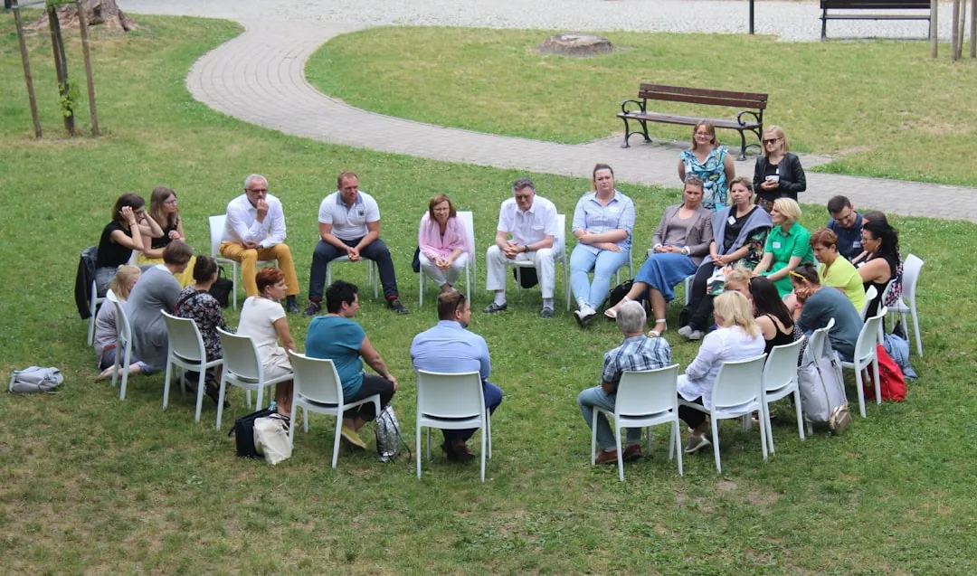 circle of people sitting on chair on grass fiedl -- Photo by Dorota Trzaska on Unsplash