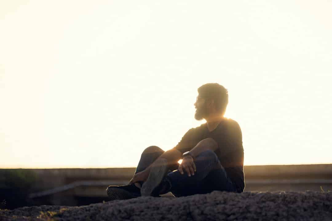 a man sitting on top of a rock near the ocean -- Photo by Kaushal Amrutiya on Unsplash