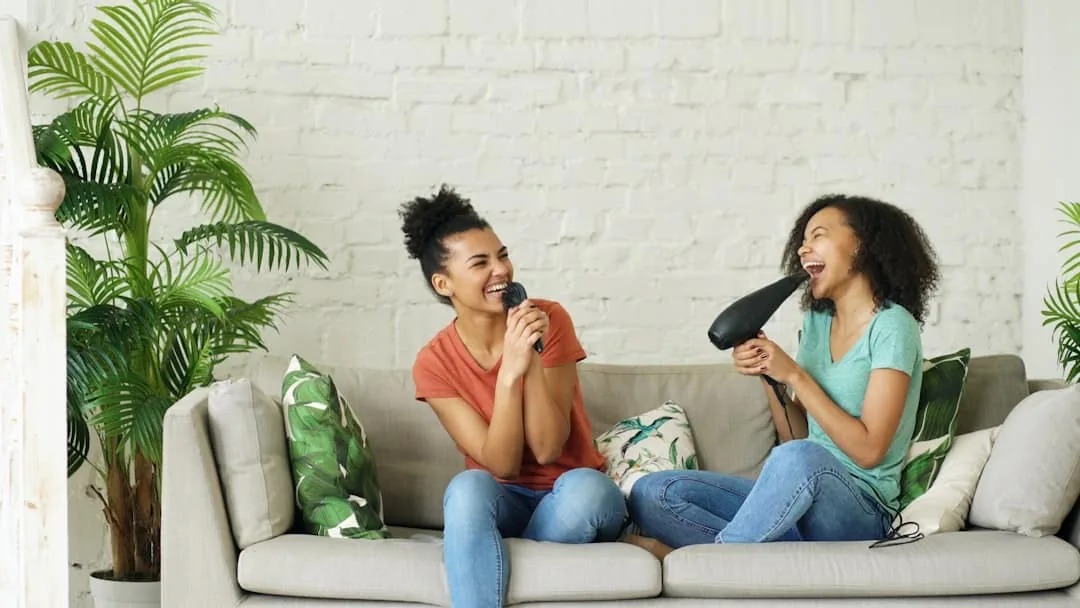 Two women singing into a microphone and hairdryer -- Photo by Vitaly Gariev on Unsplash