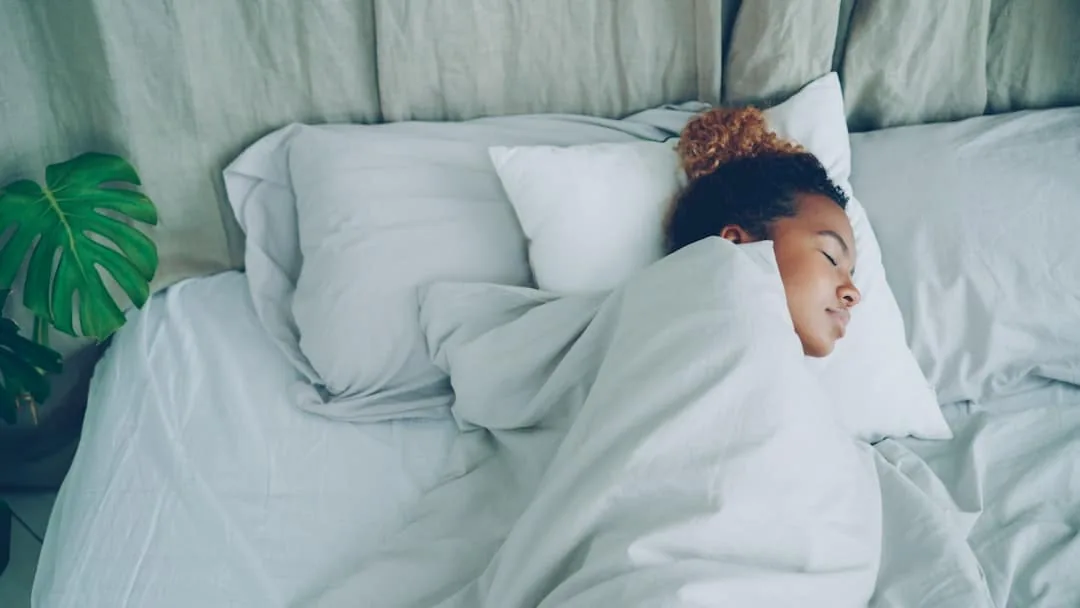 A young woman sleeping peacefully in a white bed. -- Photo by Vitaly Gariev on Unsplash