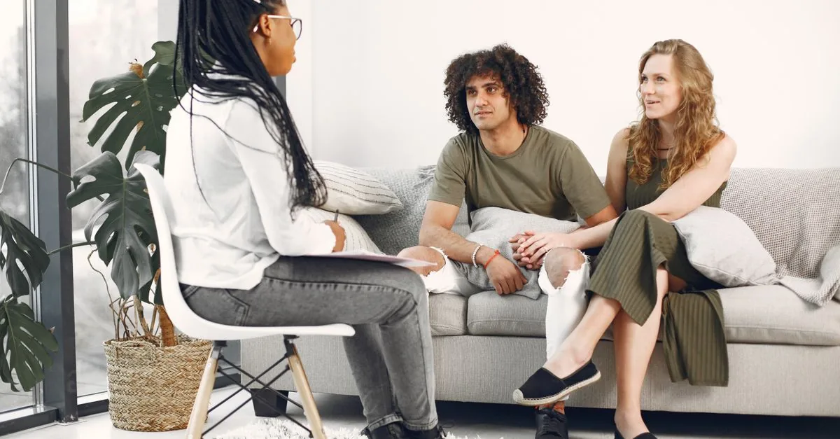 A couple engaged in a therapy session with a therapist in a stylish modern living room.