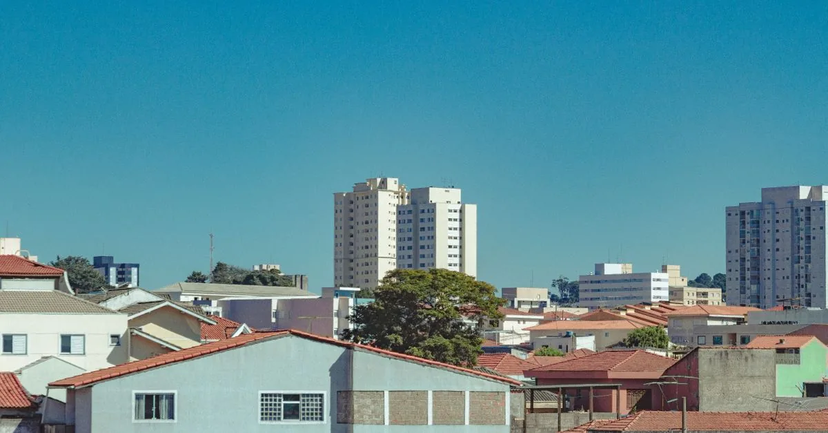Cityscape of modern district with high residential buildings and low rise houses against blue cloudless sky in summer day