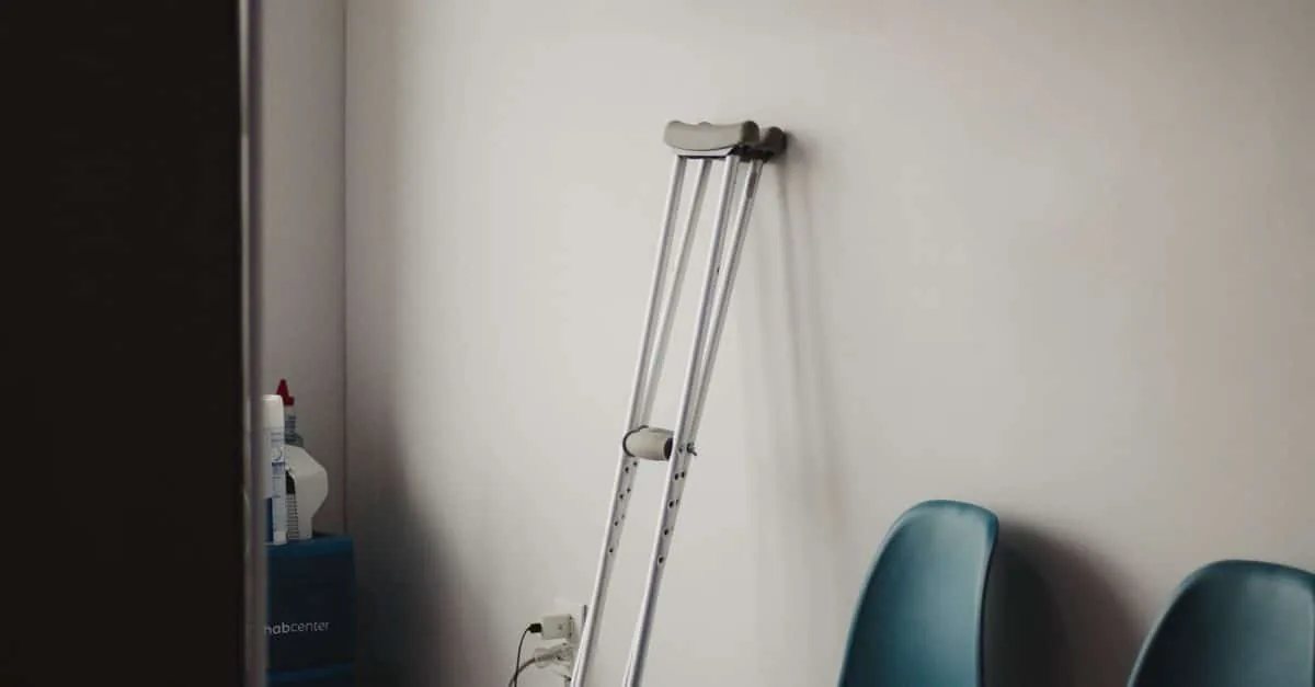 Crutches resting against a wall in a minimalist waiting room with blue chairs.