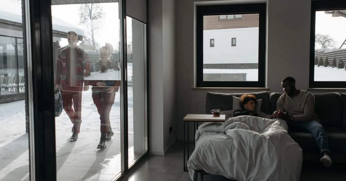 Healthcare professionals approach a patient's home through snow, providing emergency care indoors.