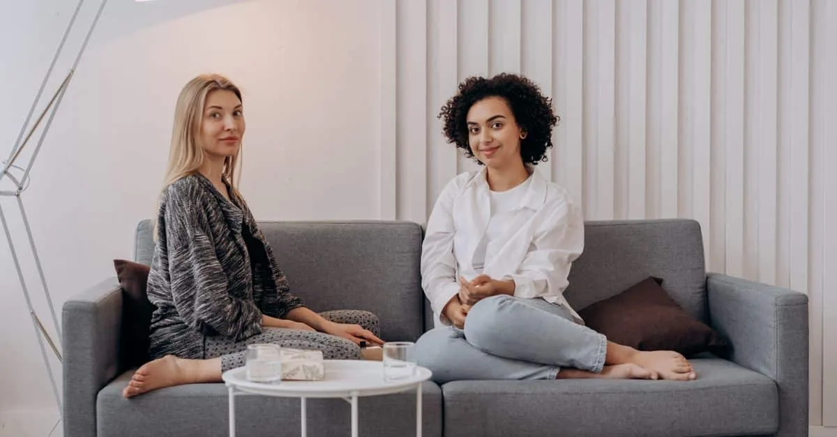 A scene of two women enjoying a comfortable moment on a stylish sofa in a well-lit room.
