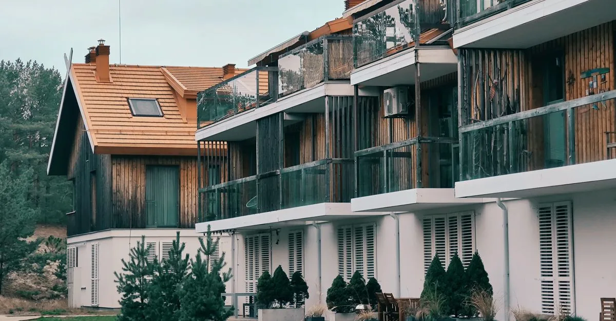 Contemporary multi-storey apartments in Nida, Lithuania showcasing wooden balconies and green surroundings.