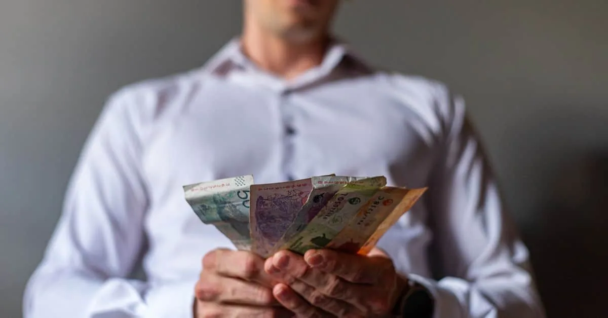 Man holding Argentine Peso banknotes in Buenos Aires, Argentina, illustrating currency concept.