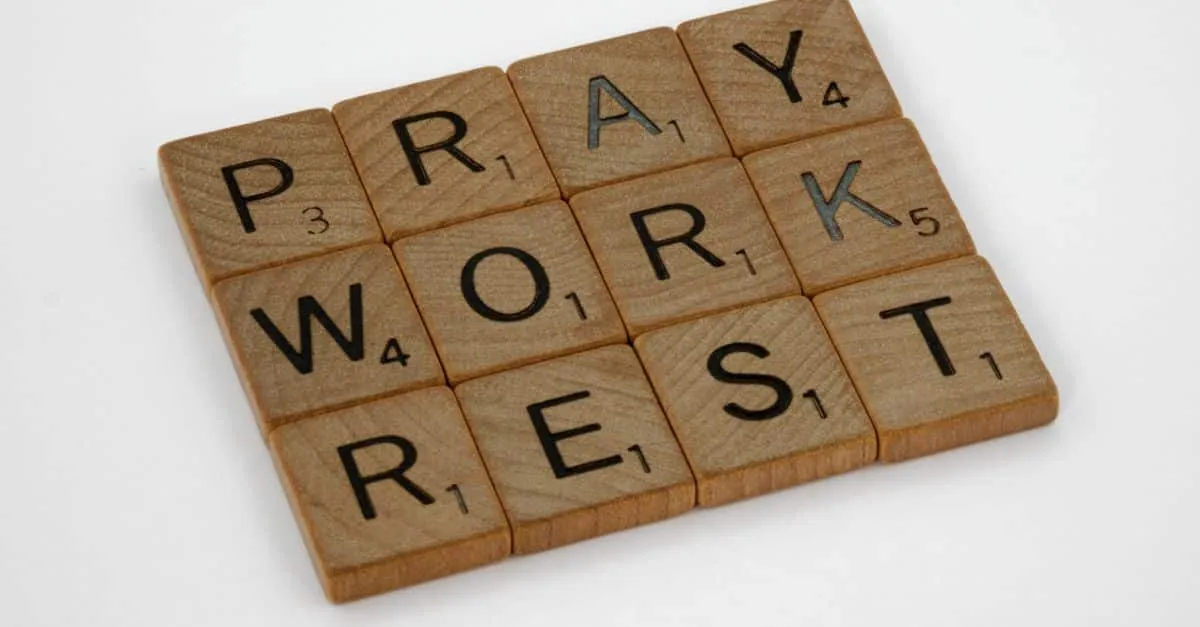 Wooden letter tiles spelling 'PRAY WORK REST' on a white background.