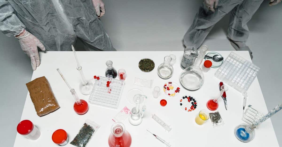 Top view of a laboratory setup with various scientific tools and substances, featuring researchers in lab coats.