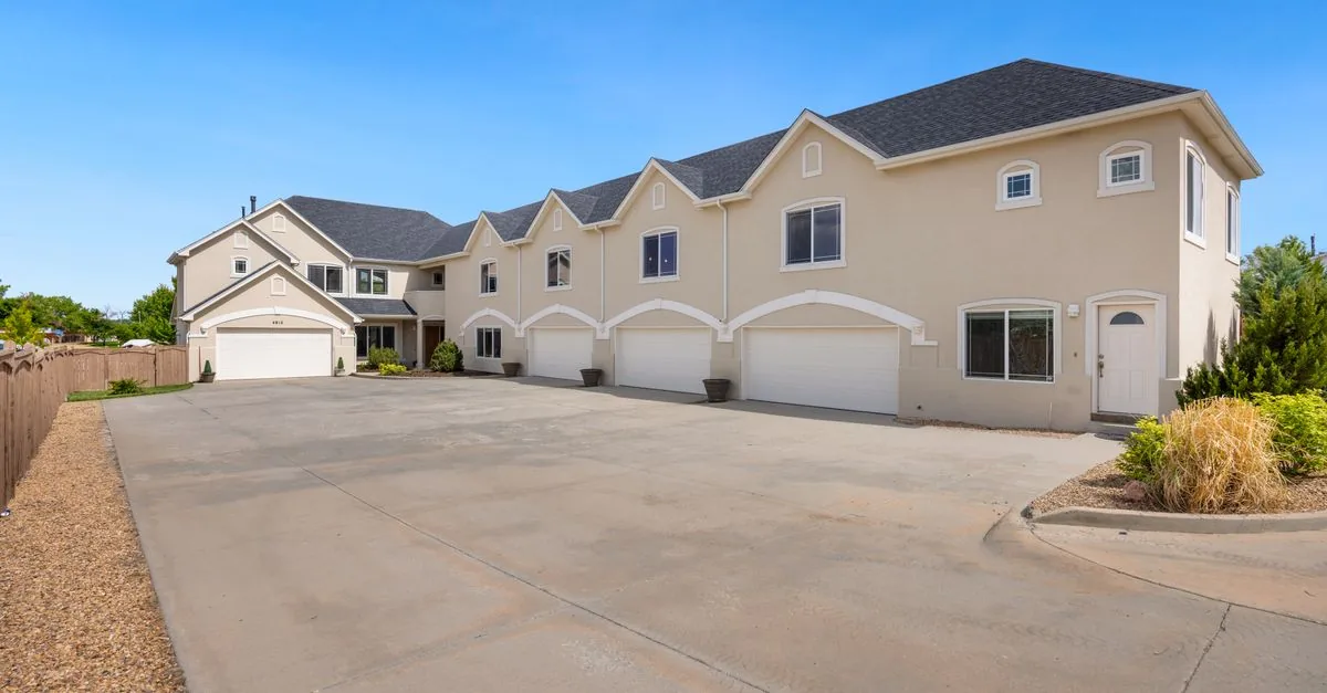A modern suburban residential building featuring a large driveway under a clear blue sky.