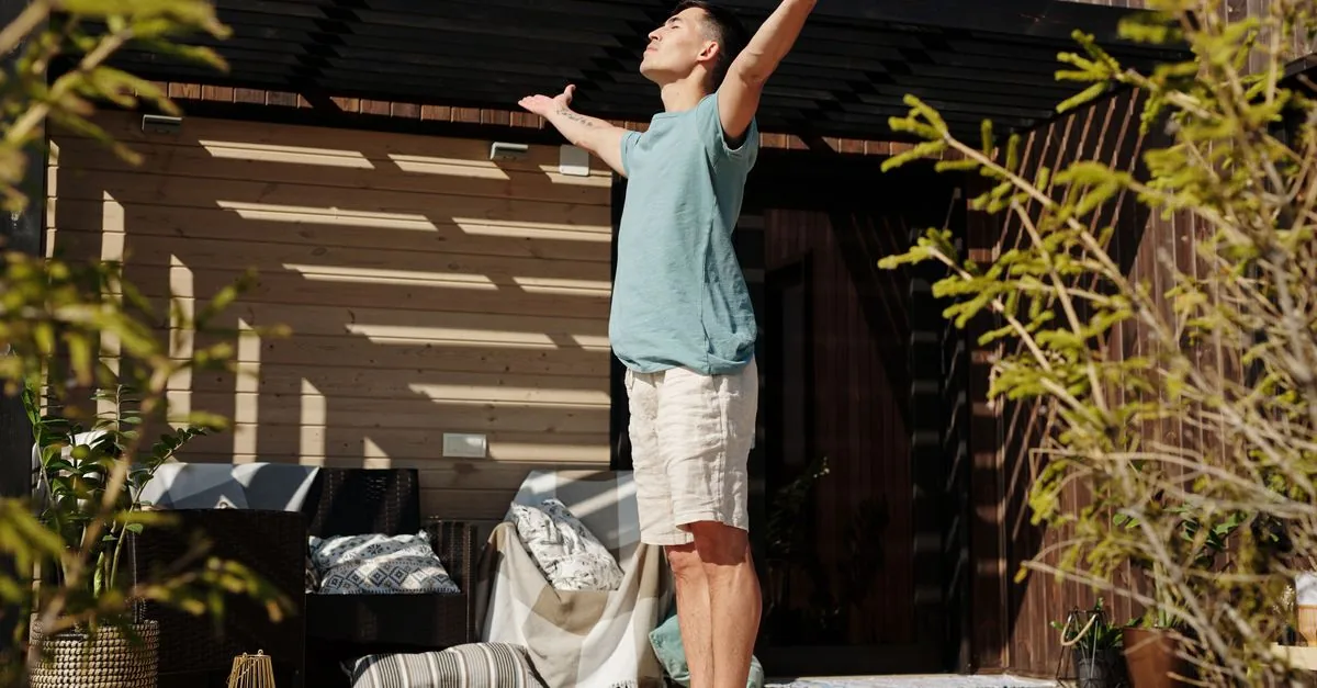 A man practicing yoga on a sunlit veranda, embracing a healthy lifestyle.
