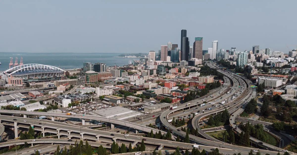 Aerial view of Seattle's downtown skyline with highways and waterfront on a clear day.