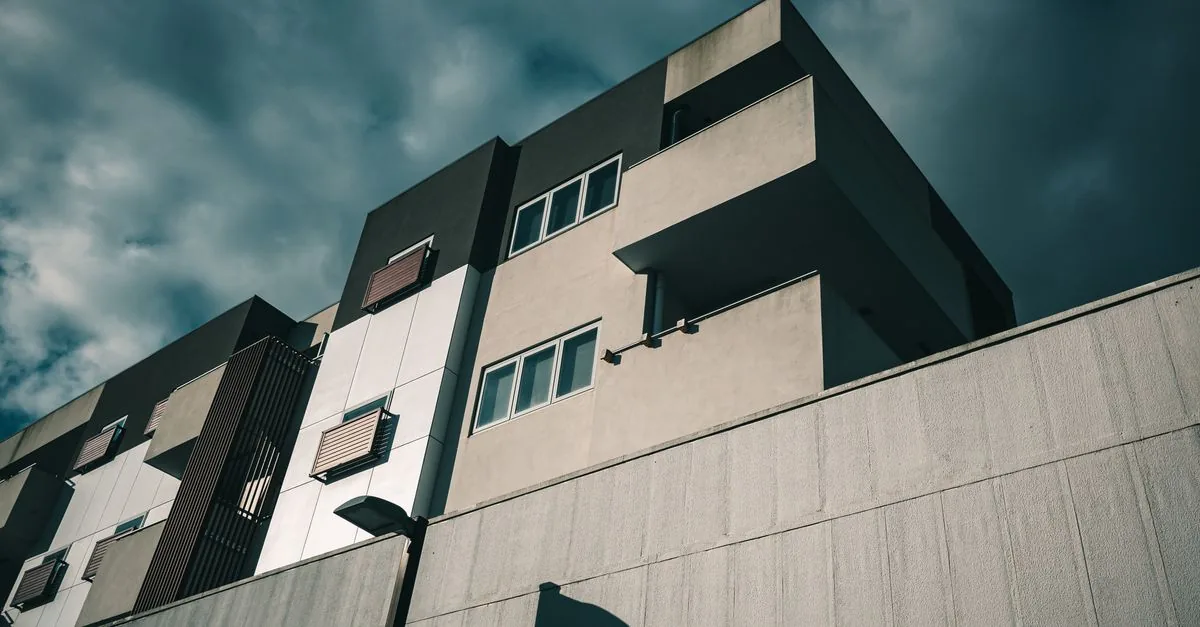 Contemporary apartment building exterior featuring balconies and glass windows from a low angle perspective.