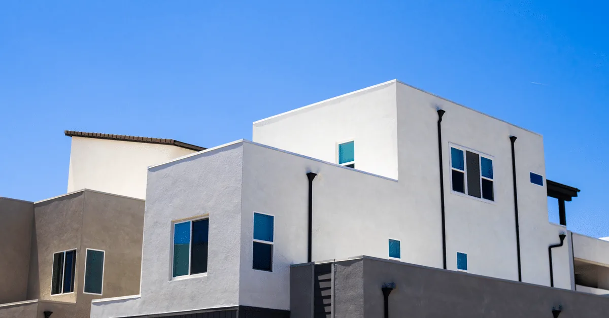 Contemporary apartment building exterior with balconies under a bright blue summer sky.