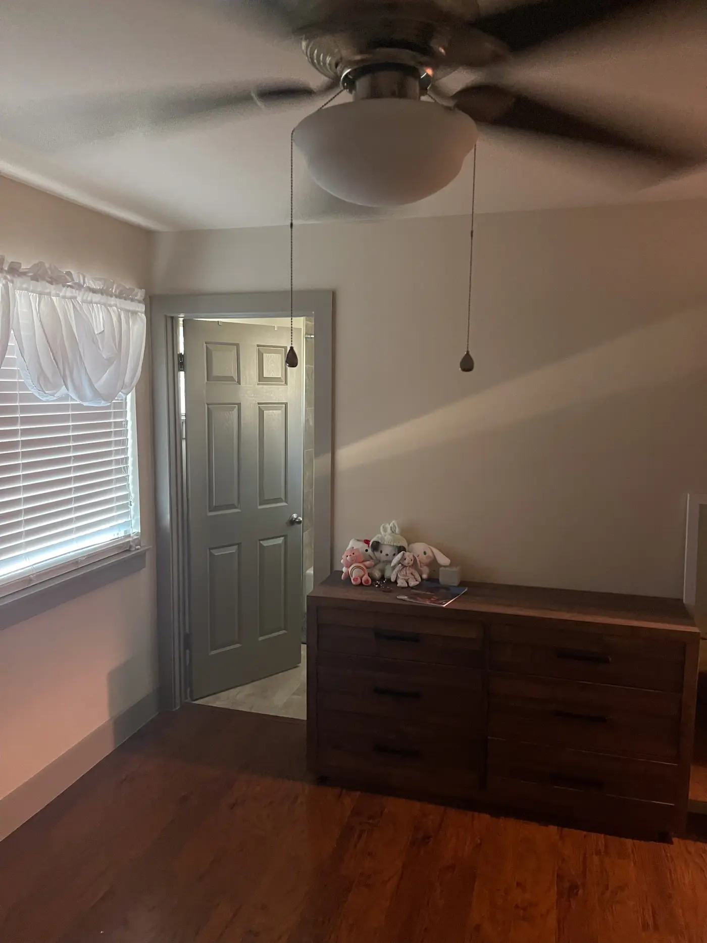 Bedroom with a wooden chest of drawers beside a shuttered window.