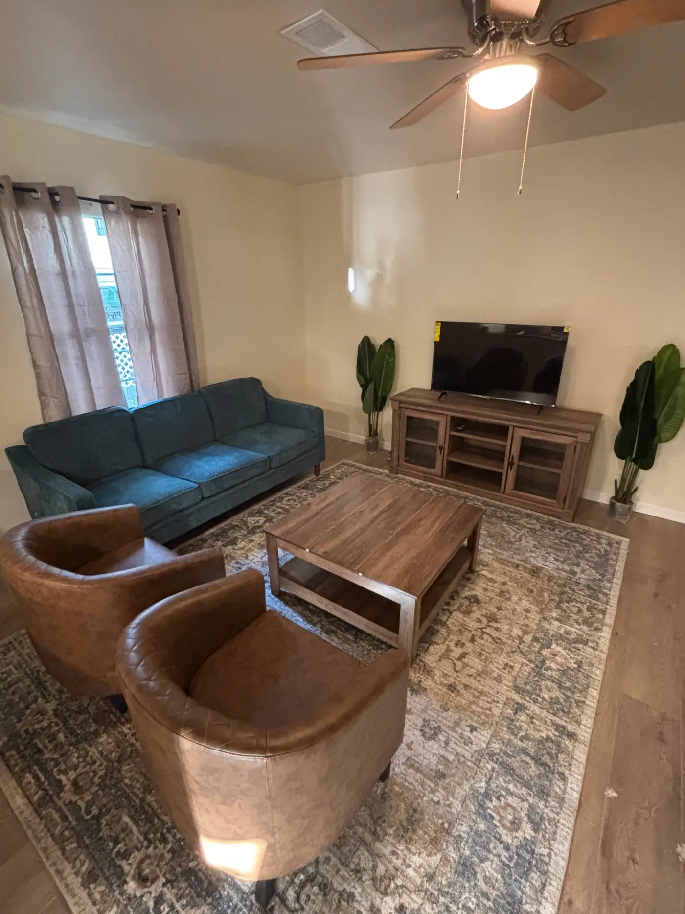 Living room with a blue sofa, two leather tub chairs and a patterned rug.