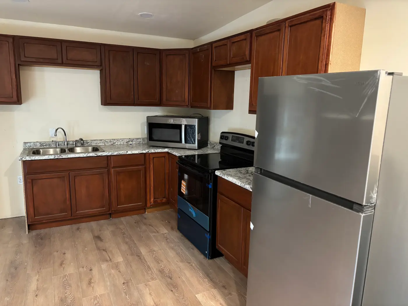 Kitchen with granite counters, a microwave and a stainless refrigerator.