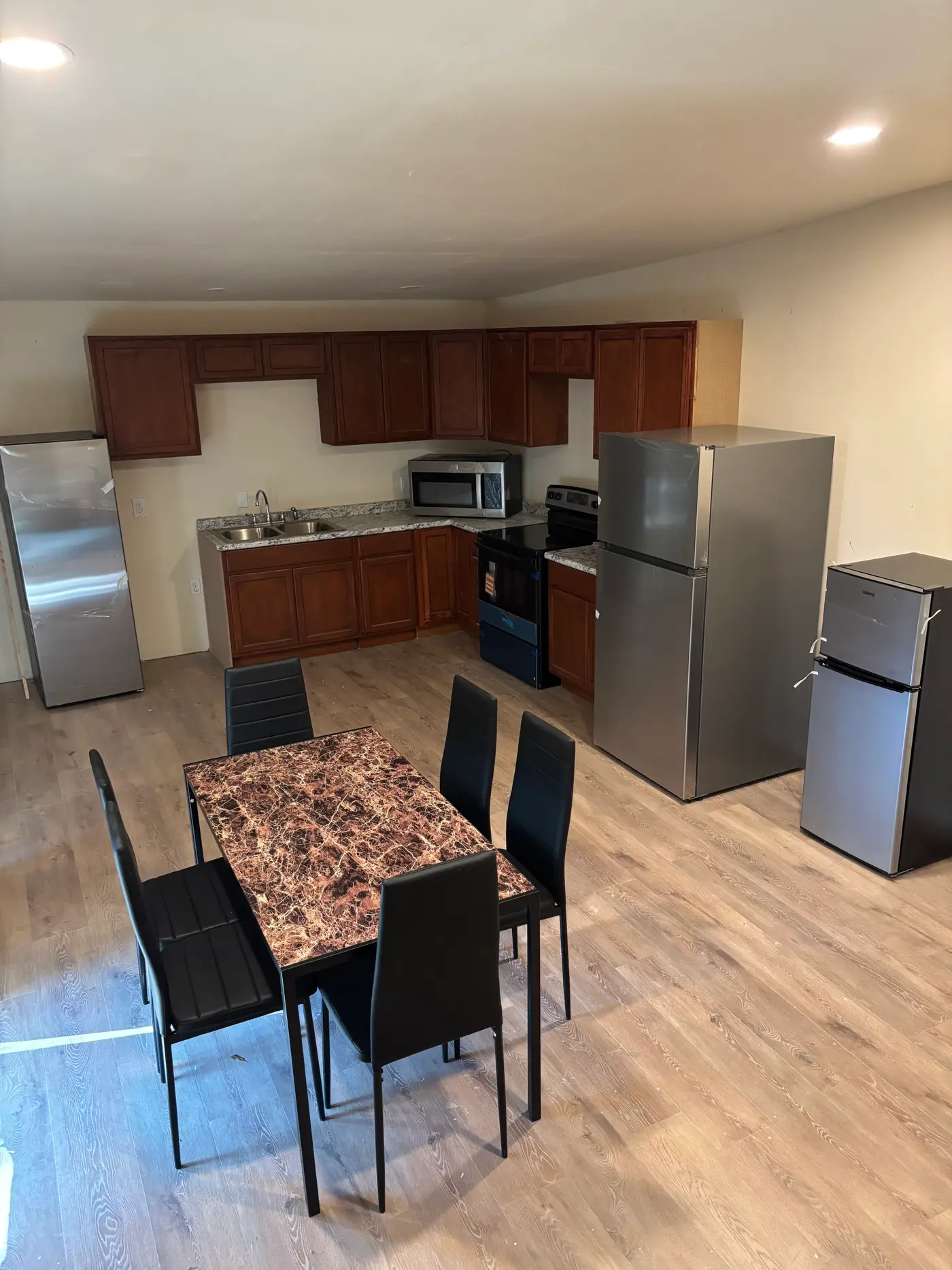 Kitchen with a dining table and chairs on pale wood flooring.