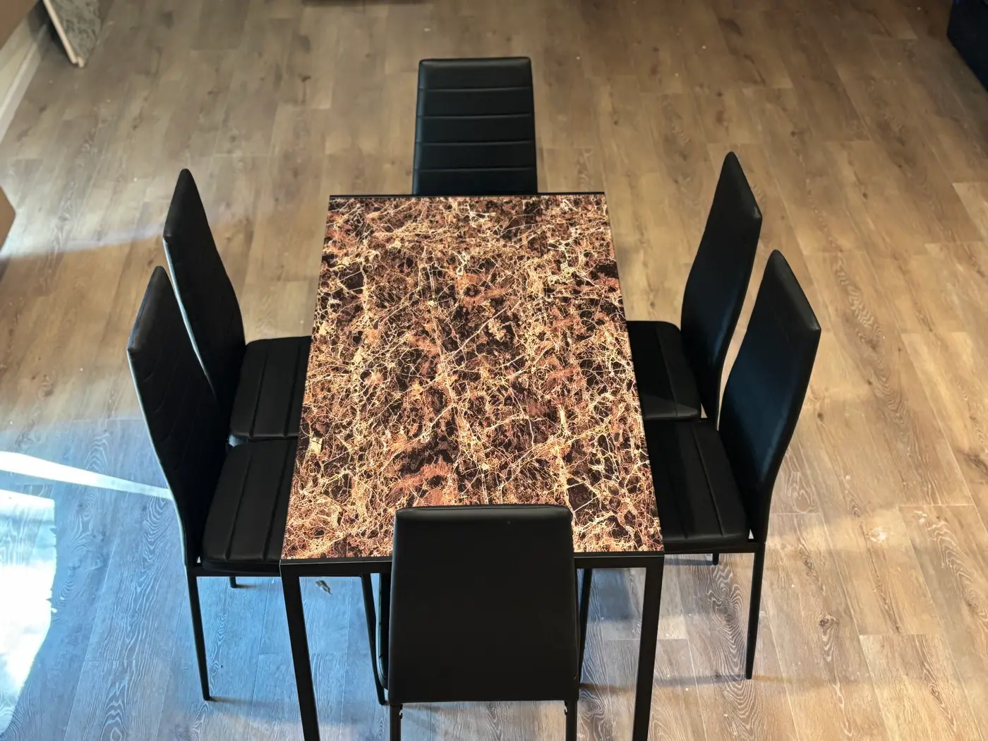 Dining table with a marble top and black chairs.