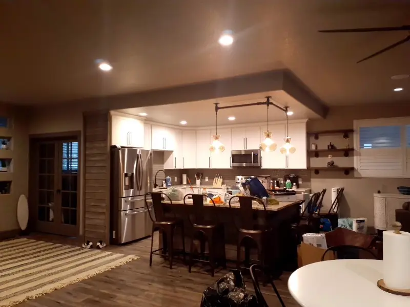 Kitchen with a stainless refrigerator, bar stools and pendant lights.