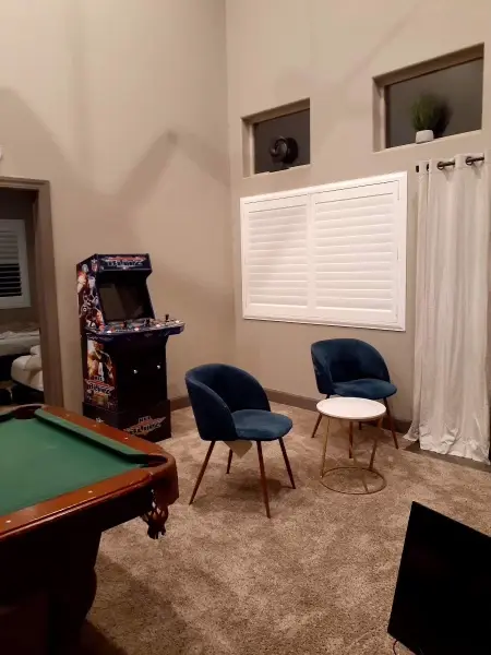 Games room with a pool table, arcade cabinet and two armchairs.