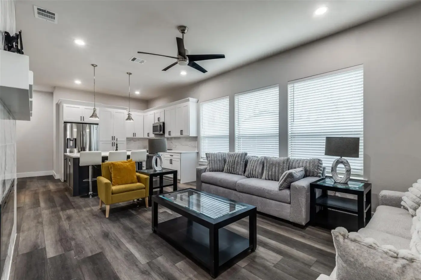 Living room with a sectional, yellow armchair and a glass coffee table.