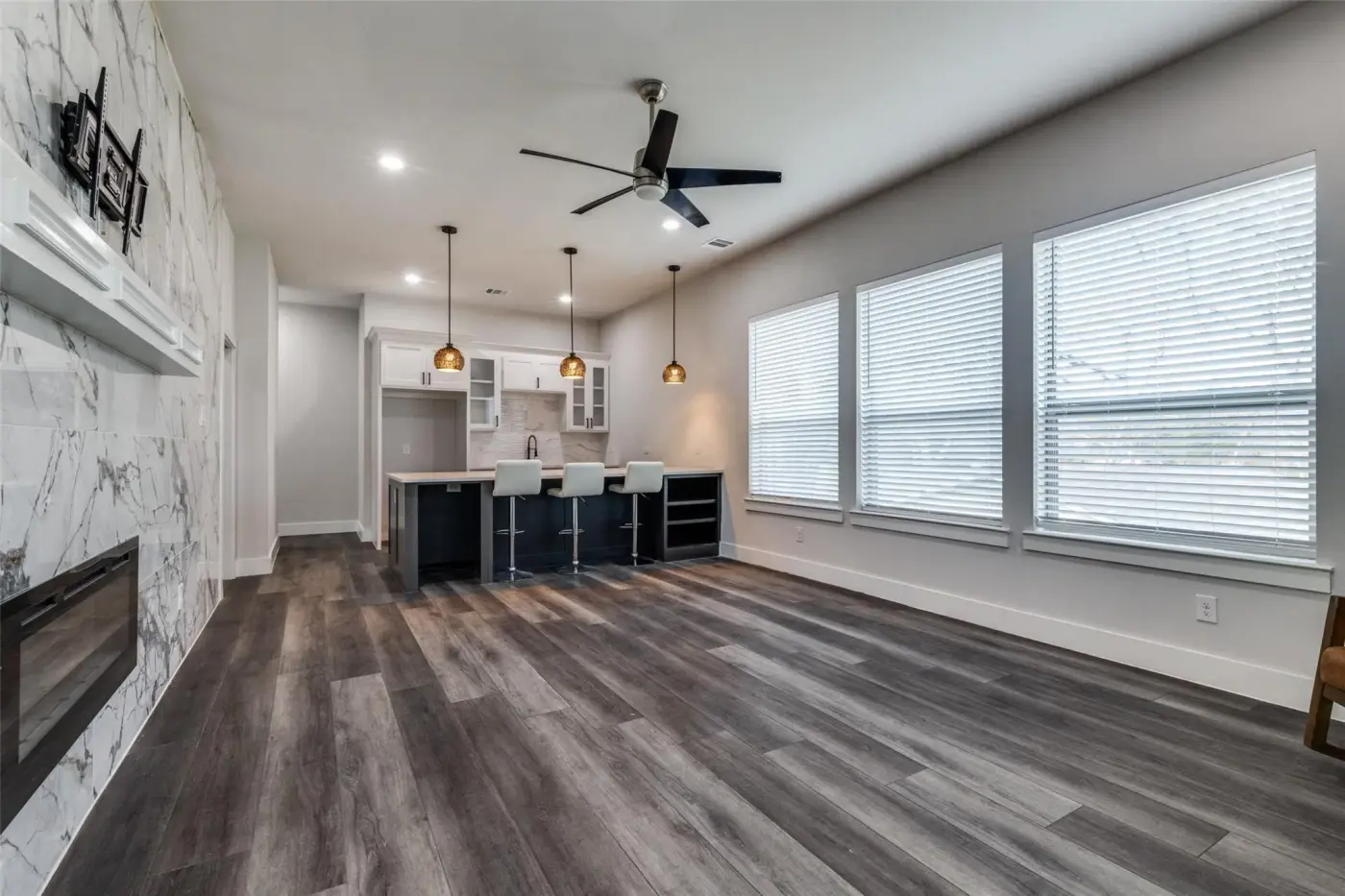 Open-plan living room and kitchen beneath a marble fireplace wall.