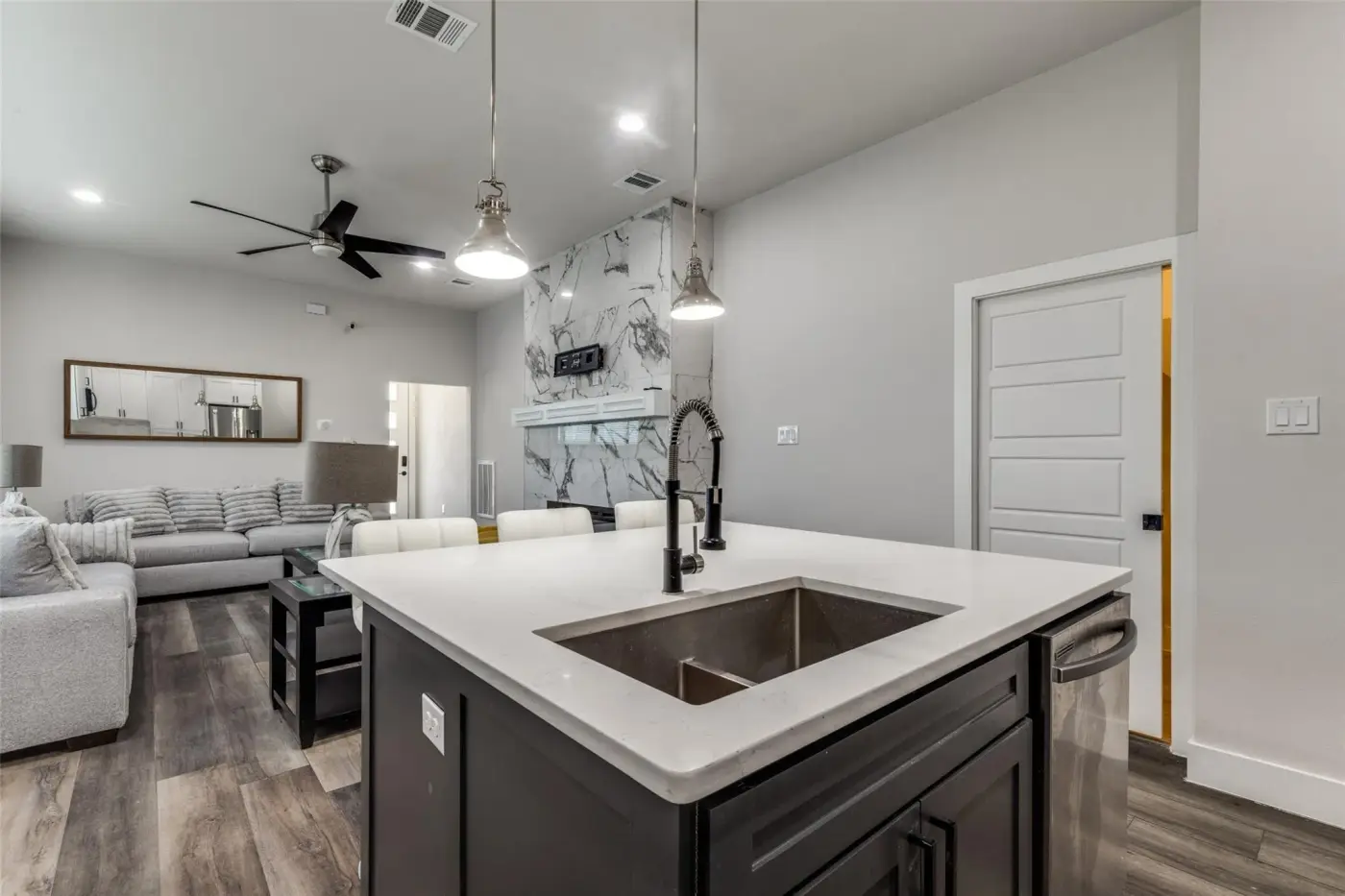 Kitchen island with a black tap and sink, looking through to the living room.