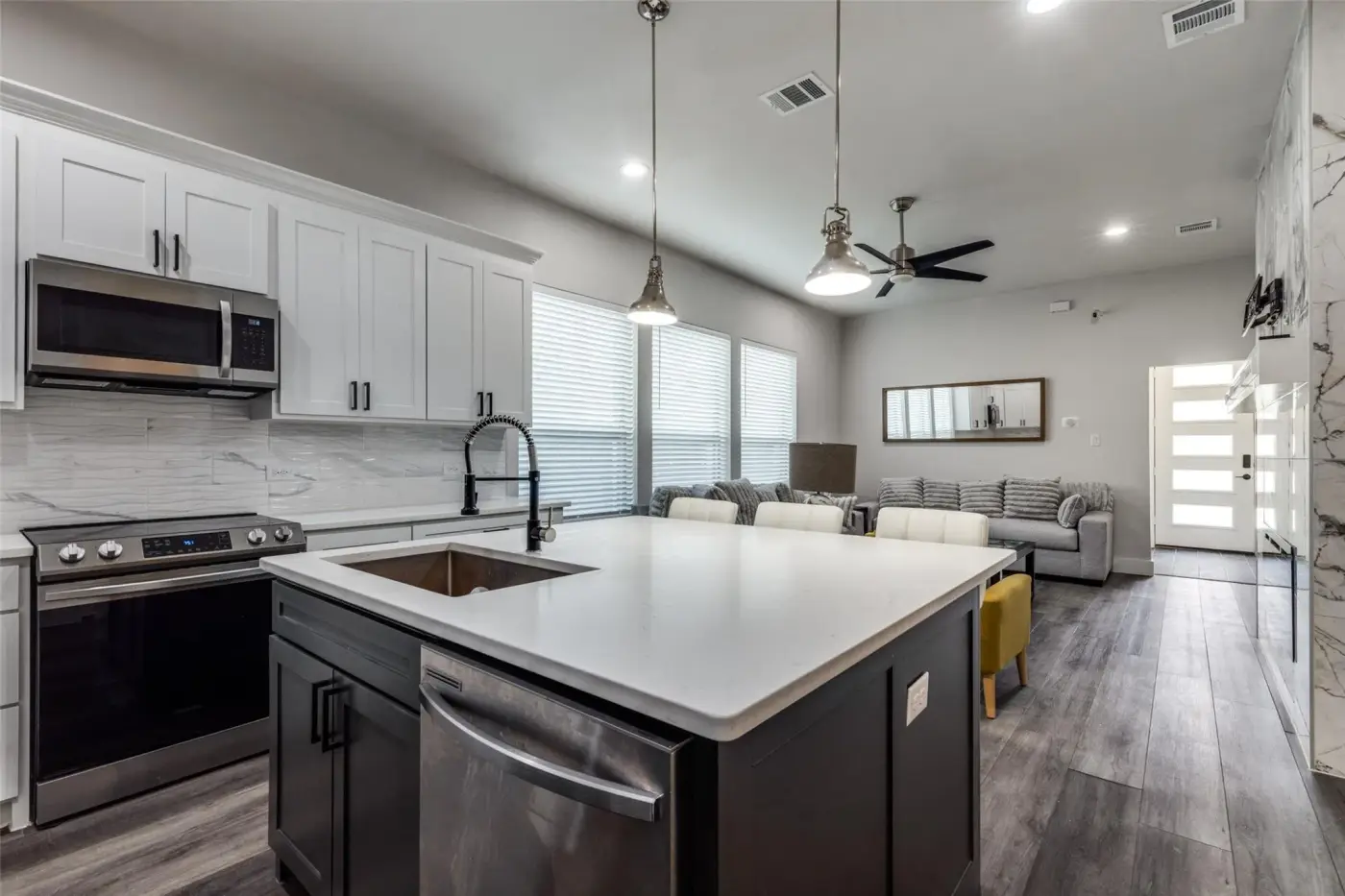 Kitchen with white cabinets, a stainless range and a quartz island.