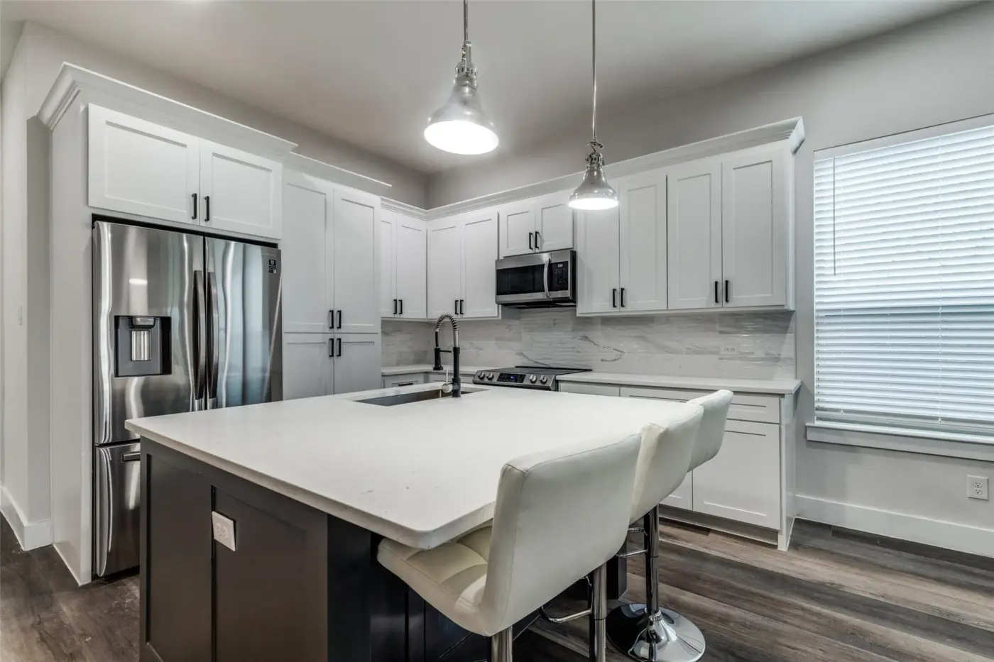 Kitchen with a quartz island, stainless refrigerator and a bar stool.