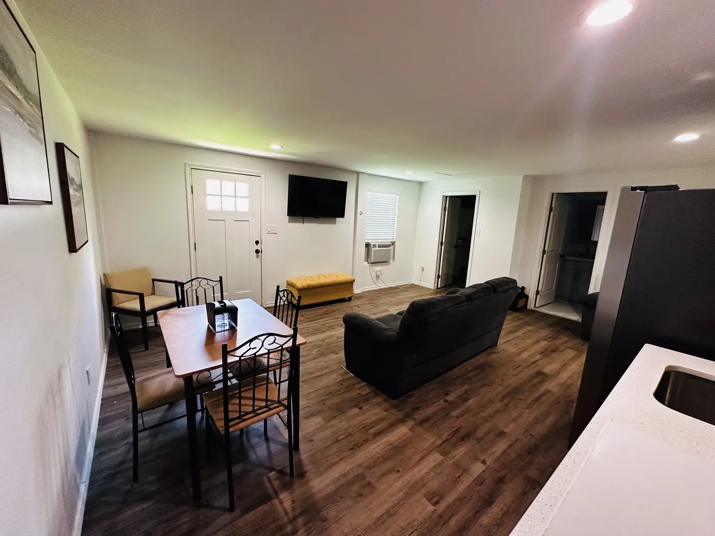 Living room with a black sofa, a television and the dining table beyond.