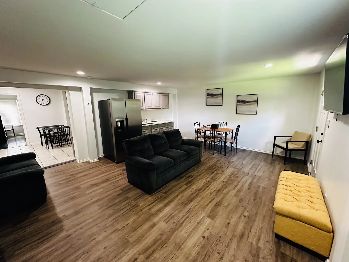Living room with a black sofa looking through to the dining area, on wood flooring.