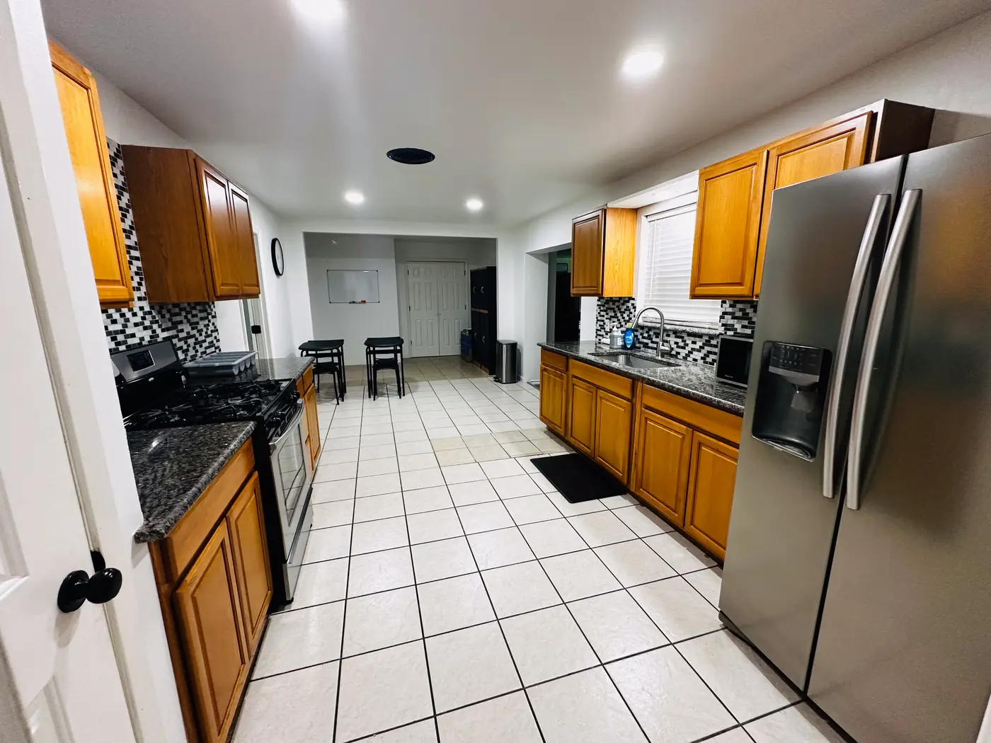 Kitchen with wood cabinets, a stainless range and refrigerator on tiled flooring.