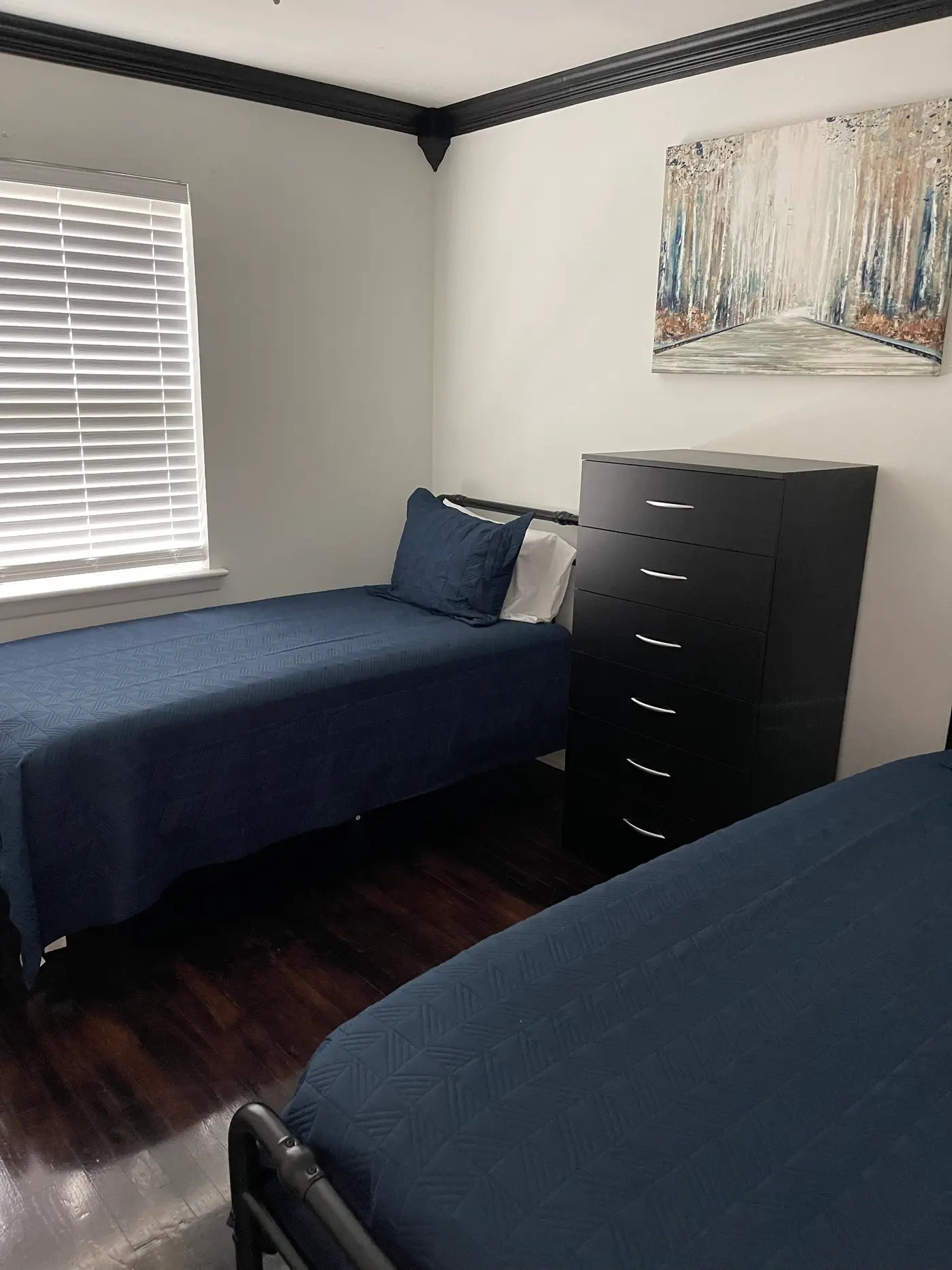 Bedroom with two single beds in blue bedding and a framed print.