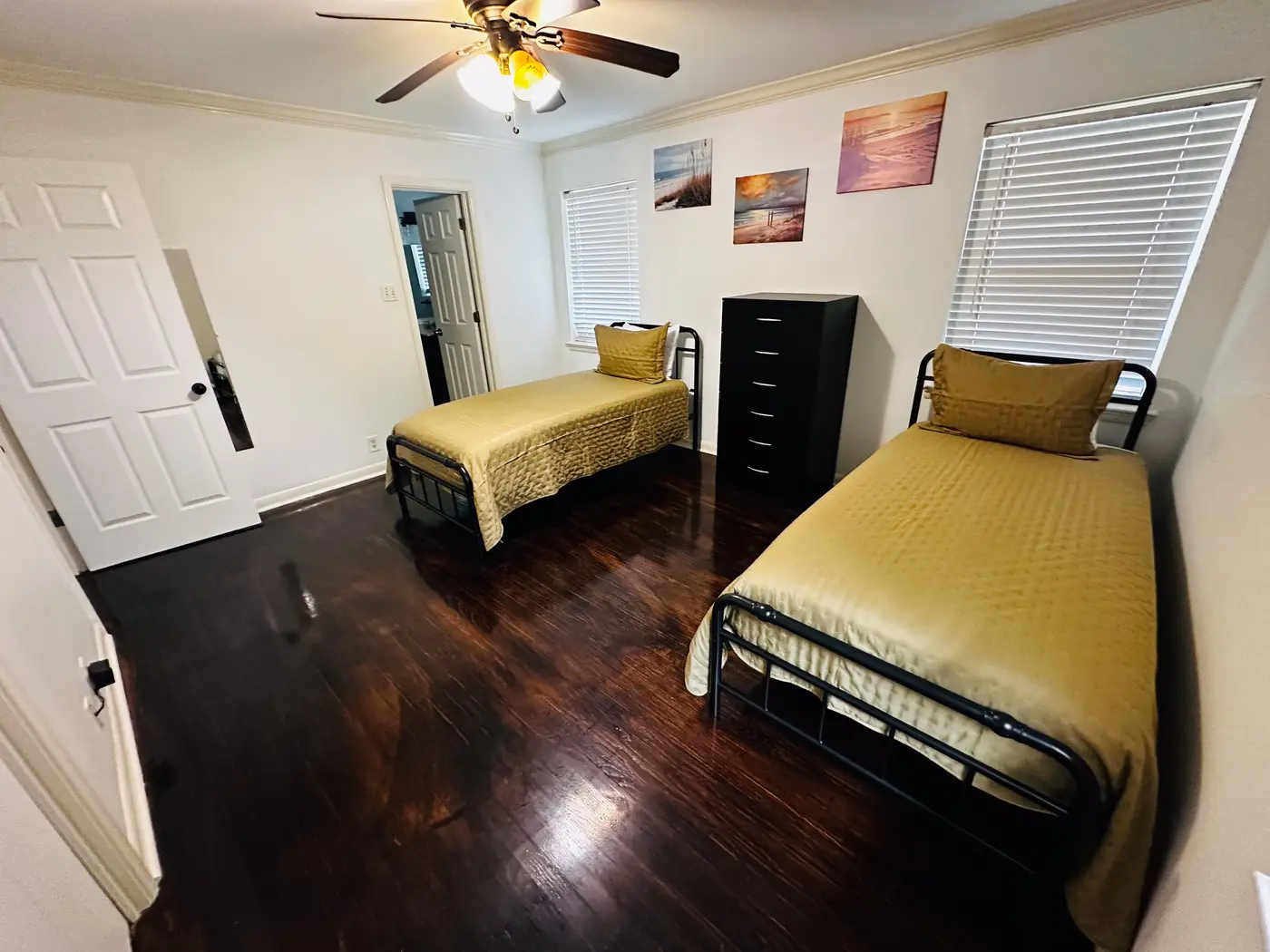 Bedroom with two single beds in gold bedding beneath a window.
