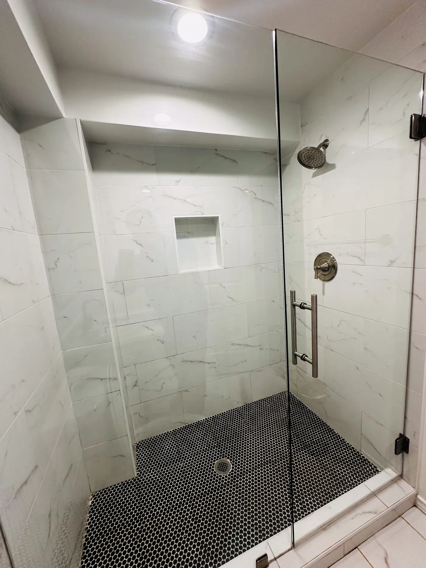 Walk-in shower with a glass screen and a tiled surround.