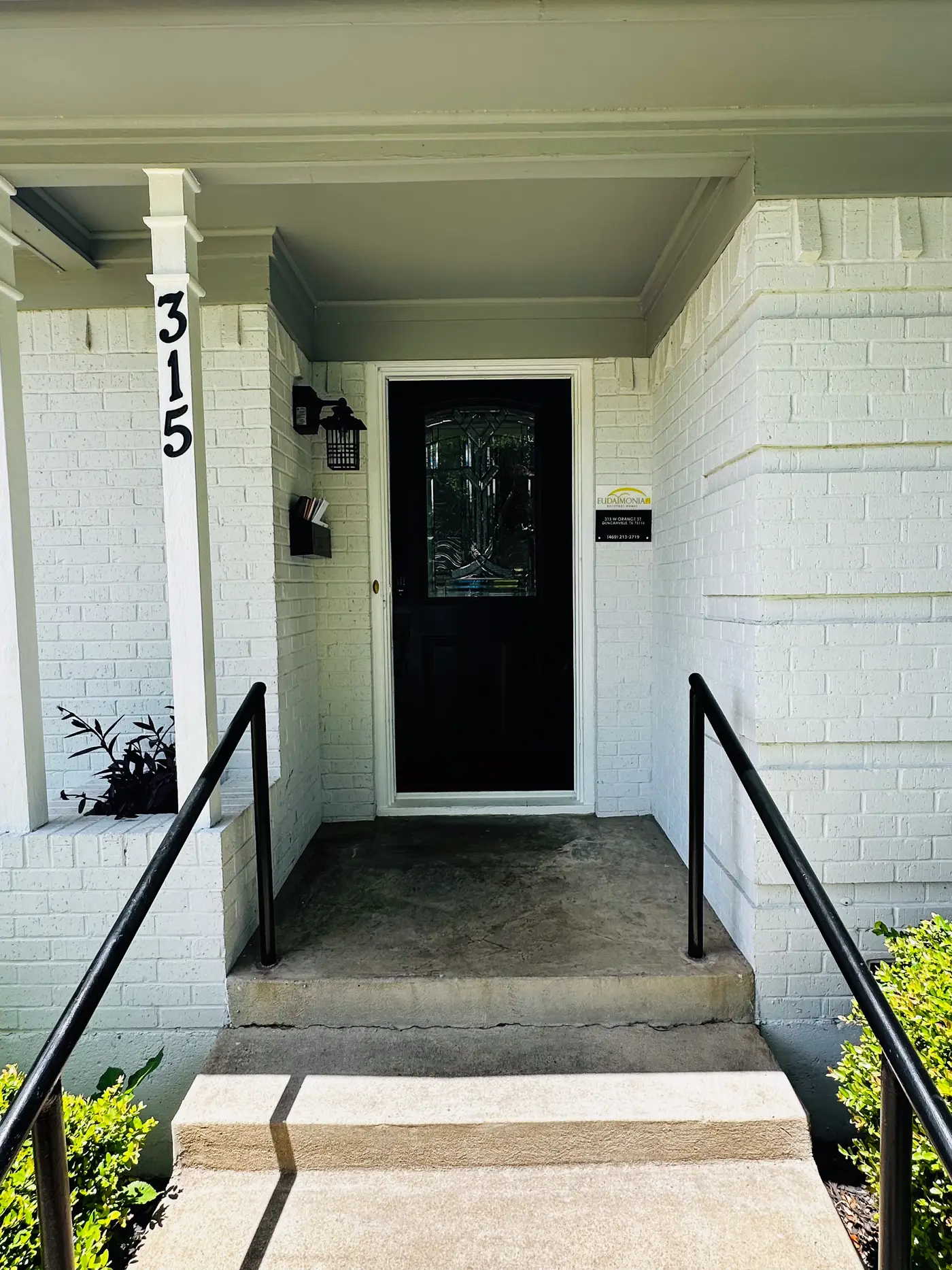 Front door of the house with the street number 315 on the porch column.